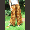 Femme en mouvement portant le pantalon fluide en lin imprimé tropical, soulignant la liberté de mouvement et le tombé élégant du vêtement confortable