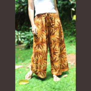 Femme en mouvement portant le pantalon fluide en lin imprimé tropical, soulignant la liberté de mouvement et le tombé élégant du vêtement confortable
