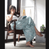 Femme assise, allure décontractée, sport-chic, vêtue d'un pantalon fluide en coton léger