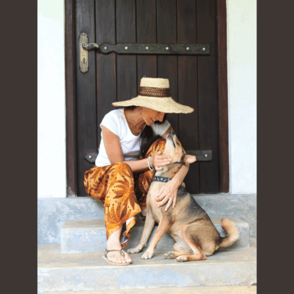 Femme assise portant un pantalon en lin fluide aux tons chaud et imprimés tropicaux caressant sont chien : style décontracté et confortable.
