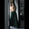Ambiance zen, face à une fenêtre. une femme porte une jupe longue et fluide en coton léger vert aux motifs ethniques dorés...